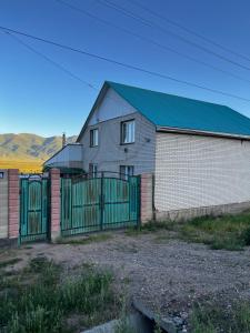 a house with a green gate and a fence at Jumgal Nomad Nest in Kyzart