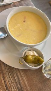 a bowl of soup on a plate with a spoon at Bran Pensiunea Restaurant Al Gallo centru in Bran