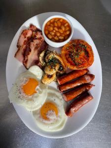 a plate of breakfast food with eggs bacon beans and meat at Bran Pensiunea Restaurant Al Gallo centru in Bran