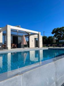 ein Schwimmbad mit Sonnenschirmen vor einem Gebäude in der Unterkunft Villa Yi in Chorafakia