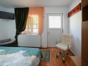 a bedroom with a bed and a chair and a window at CASA DODO in Călimăneşti