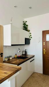 a kitchen with white cabinets and a wooden counter top at Apartament Piaskowy Kołłątaja in Tomaszów Mazowiecki