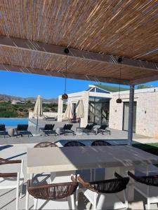 eine Terrasse mit Tisch und Stühlen und einem hölzernen Sonnenschirm in der Unterkunft Villa Yi in Chorafakia