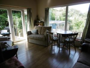 a living room with a couch and a table with chairs at 2 Little Meadow Cottages in Dartmouth
