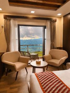 a hotel room with a bed and chairs and a large window at Kanyam Brichyalaya in Suryodaya