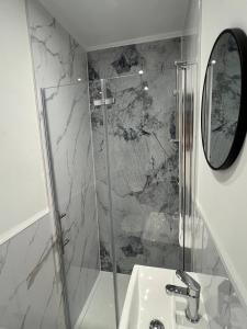 a bathroom with a shower with a sink and a mirror at Melton House in Houghton Regis