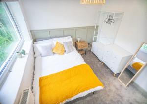 a bedroom with a bed with a yellow blanket at Melton House in Houghton Regis