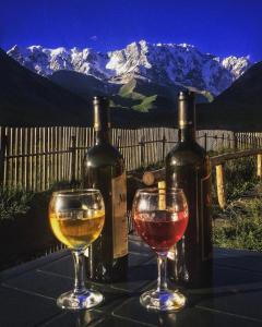 two glasses of wine sitting on a table with wine bottles at LEMI Mountain Cottages - Ushguli in Ushguli