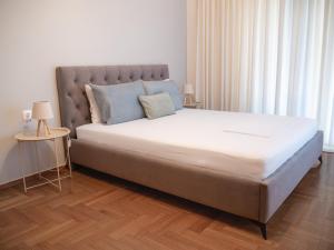 a bedroom with a large bed with white sheets and blue pillows at Central Family Flat Volos in Volos