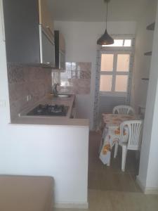 a kitchen with a sink and a table with chairs at Au Soleil le Vent in La Goulette