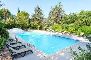 a swimming pool with lounge chairs and an umbrella at Chalet confort 4 piscine partagée in Les Vans
