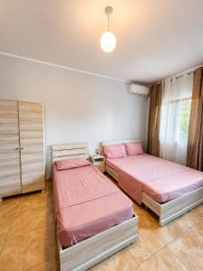 two beds in a bedroom with pink sheets at Hotel Marino in Baks-Rrjoll