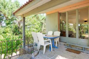a porch with a table and white chairs on it at Chalet confort 4 piscine partagée in Les Vans