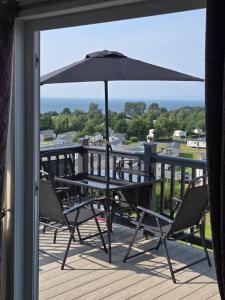 a balcony with a table and chairs and an umbrella at Glen lodge Craig Tara in Ayr
