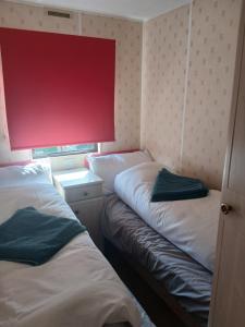 two beds in a small room with a red wall at Hillcrest hideaways2 in Hunmanby