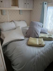 a white bed with pillows and a towel on it at Hillcrest hideaways2 in Hunmanby