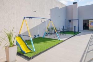 a playground with a swing and grass at Peaceful Stay with Rooftop Pool Access in Fernando de la Mora