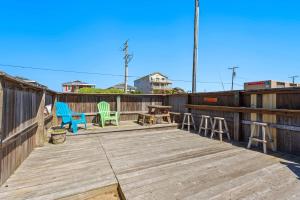 a wooden deck with chairs and a table on it at 5065 - Flip Flop Inn in Kill Devil Hills