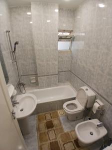 a bathroom with a toilet and a sink and a tub at California Stay in Amman