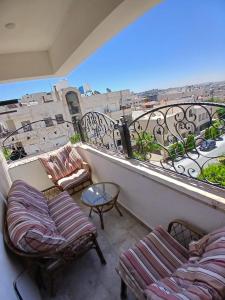 a balcony with chairs and a view of a city at California Stay in Amman