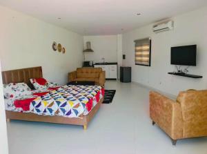 a bedroom with a bed and a couch and a television at Izuba in Ngaparou