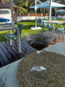 a glass of red wine sitting on a table at Roulotte Beach São Tomé in Triunfo