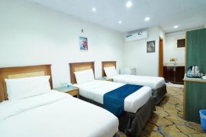 a hotel room with three beds in it at فندق ندى الفيروز in Az Zāhir