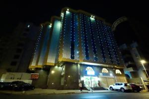 a large building with blue lights on it at night at فندق ندى الفيروز in Az Zāhir