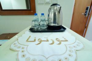 a table with a cake with a blender and water bottles at فندق ندى الفيروز in Az Zāhir