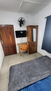 a bedroom with a bed and a desk and a television at Le perchoir bleu in Lomé