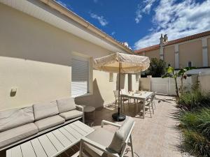 a patio with a couch and an umbrella and a table at Desbo in Valras-Plage
