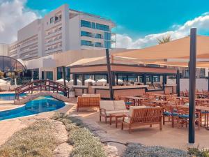 a patio with tables and chairs and a building at Adams Beach Hotel & Spa in Ayia Napa