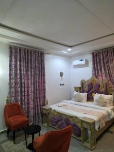 a bedroom with a large bed and two chairs at Single Room in Abuja
