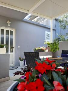 a patio with a table with red flowers on it at Apartman Jadranka in Rogotin