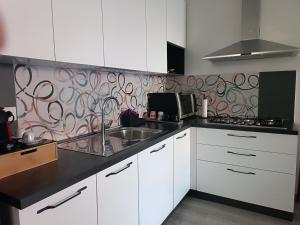 a kitchen with white cabinets and a sink and a wallpaper at L'angolo di Cinzia in Matera