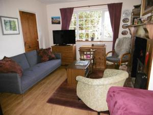a living room with a blue couch and a tv at 2 Little Meadow Cottages in Dartmouth