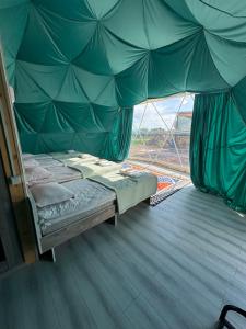 a bed in a green tent with a window at Meykin Glamp in Cholpon-Ata