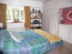 a bedroom with a bed with a blue and green blanket at 2 Little Meadow Cottages in Dartmouth