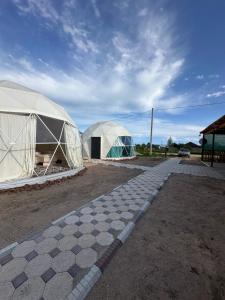 two large domes in a field with a checkered at Meykin Glamp in Cholpon-Ata