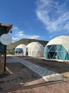 three domes are lined up in a field at Meykin Glamp in Cholpon-Ata