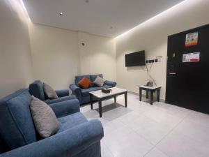 a living room with two blue couches and a tv at وتد الشرق للشقق المخدومة in Khafji