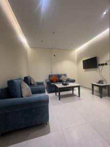 a living room with two blue couches and a tv at وتد الشرق للشقق المخدومة in Khafji +7 photos