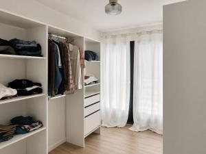 a walk in closet with white shelves and a window at Cocon hyper centre de Pau avec parking in Pau