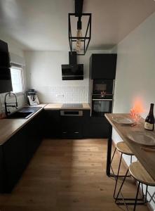 a kitchen with black and white appliances and a wooden floor at La Maison Cocoon in Étampes +2 photos