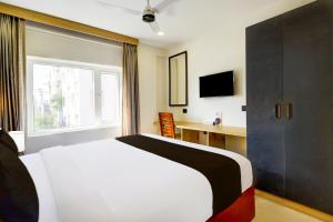 a bedroom with a bed and a desk and a window at Townhouse Aarav Business Hotel in Hyderabad