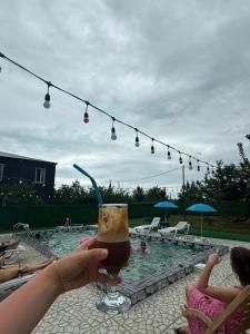 a person holding a drink in front of a swimming pool at Dore in Kobuleti in Kobuleti