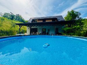 a villa with a swimming pool in front of a house at Green Hills - Holiday Home & Events in Kamenica