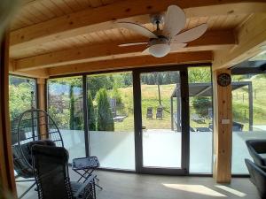 a screened in porch with a ceiling fan and glass doors at Romantic Mountain Chalet and SPA Tubej in Bohinj