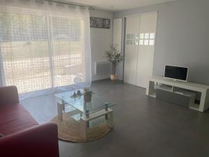 a living room with a couch and a glass table at Apartment 65 m2 SE Rez de Jardin 2 chambres in Varetz