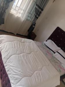 a white bed in a bedroom with a window at Kings Hotel and Lounge in Bwari
